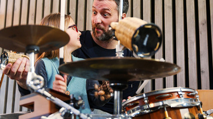 Father and daughter enjoy play music together.Little girl smiling learning drums with her dad at...