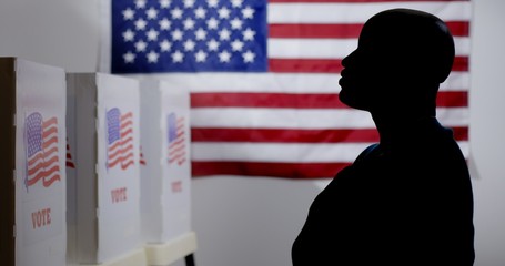 MS silhouetted African American man looking at voting booths, with hand over heart, US flag on wall...