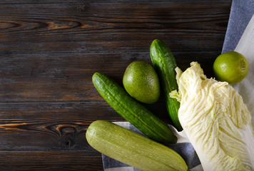 salad, lime, cucumber, zucchini, avocado, on a towel on a brown wooden , fresh green vegetables and citrus top view