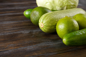 zucchini, acucumber, avocado, lime, salad on a towel on a brown wooden background, fresh green vegetables and citrus