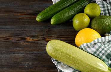 zucchini, avocado, cucumber, lemon, lime, lemon, towel on a wooden background, fresh green and yellow vegetables and citrus,