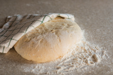 Yeast dough in flour lies on a stone table in the kitchen