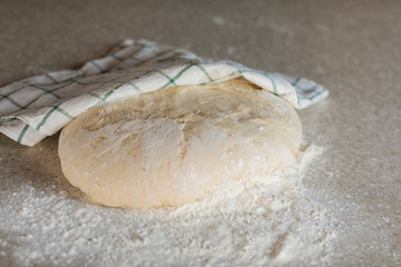 Yeast dough in flour lies on a stone table in the kitchen