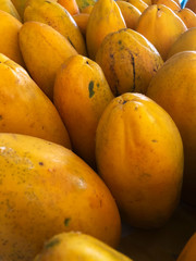 Yellow orange papayas are stacked close together ready for sale