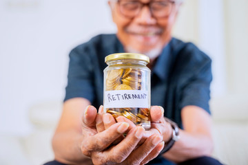 Happy senior man showing a jar full of coins
