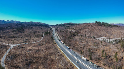 Traffic jam on the motorway or highway. Aerial drone photo of trucks or lorries stuck in a traffic jam over the country. Long queue of semi trailers on a motorway