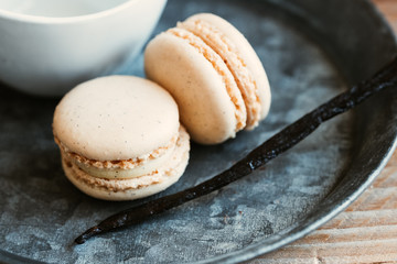 Deux macarons à la vanille et gousse de vanille sur un plat en métal
