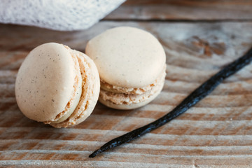 Deux macarons à la vanille et gousse de vanille sur une planche en bois