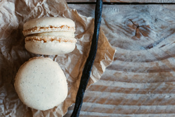 Deux macarons à la vanille et gousse de vanille sur une planche en bois