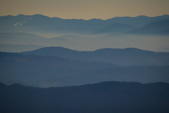Different lines of hills slowly fading into the distance. Fog and mist visible between the valleys in the mountains. Good background photo, mystcal hills.