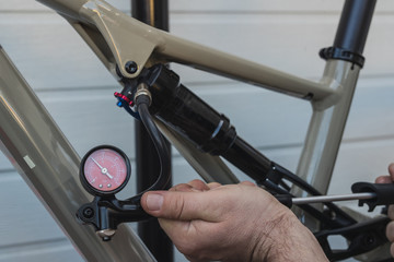 Pumping the rear shock or absorber of a modern mountain bicycle using a hand pressure pump. Setting sag on bicycle air shock.