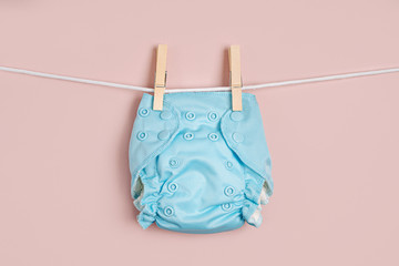 Reusable cloth baby diapers drying on a clothes  line. Eco friendly cloth nappies on a pink...
