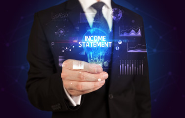Businessman holding lightbulb with INCOME STATEMENT inscription, Business idea concept