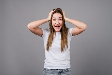 Fototapeta premium woman holding head smiling and screaming isolated on grey background