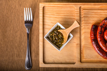 Chimichurri sauce and chistorra on a wooden cutting board, fork