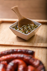 Chimichurri sauce and chistorra on a wooden cutting board