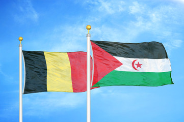 Belgium and Western Sahara two flags on flagpoles and blue cloudy sky