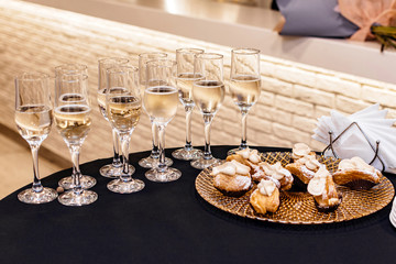 Champagne in glasses and a plate with cakes on the table
