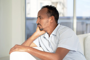 Sad face depressed african man. Portrait of a sad man close-up. Lonely african man is sad sitting on the bed at home. Man feel depression.
