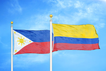 Philippines and Colombia two flags on flagpoles and blue cloudy sky