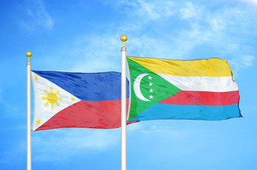 Philippines and Comoros two flags on flagpoles and blue cloudy sky