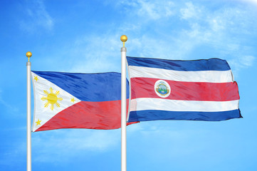 Philippines and Costa Rica two flags on flagpoles and blue cloudy sky