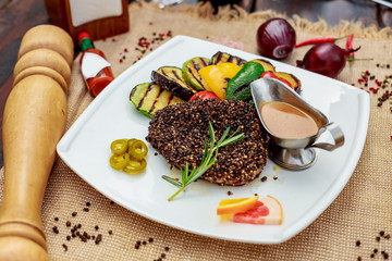 A large steak with spices and vegetables on the grill