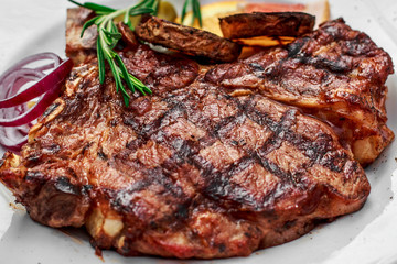 A large steak with spices and vegetables on the grill