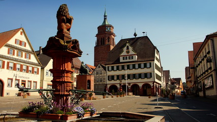 schöner alter Marktplatz in Weil der Stadt mit Kirchturm, Rathaus und Brunnen vor blauem Himmel