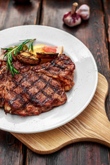 A large steak with spices and vegetables on the grill