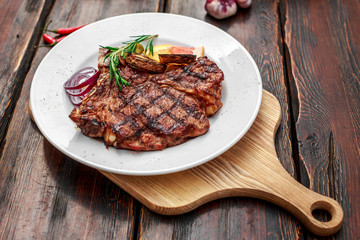 A large steak with spices and vegetables on the grill