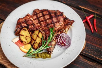 A large steak with spices and vegetables on the grill