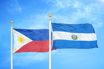 Philippines and El Salvador two flags on flagpoles and blue cloudy sky