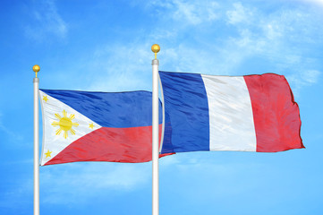 Philippines and France two flags on flagpoles and blue cloudy sky