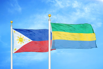 Philippines and Gabon two flags on flagpoles and blue cloudy sky