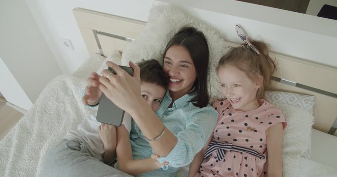 mother and children playing taking selfie