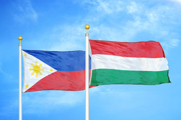 Philippines and Hungary two flags on flagpoles and blue cloudy sky