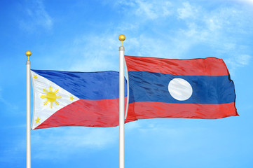 Philippines and Laos two flags on flagpoles and blue cloudy sky