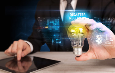 Businessman holding lightbulb with DISASTER RECOVERY inscription, online security idea concept