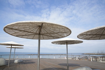 
White beach umbrellas on the background of the sea and blue sky. Cafe or space for relaxation. Space for text. Vacation and tourism concept