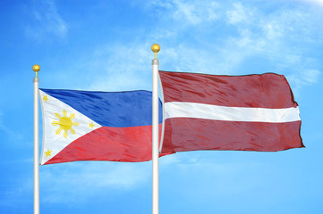 Philippines and Latvia two flags on flagpoles and blue cloudy sky