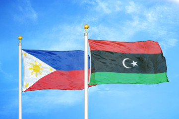 Philippines and Libya two flags on flagpoles and blue cloudy sky