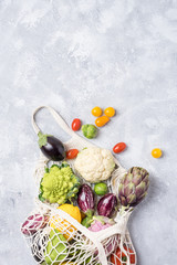 Different farm vegetables in a home string bag. Gray background. The concept of healthy eating.
