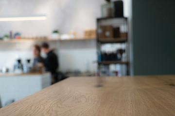 Cafe background. It is visible part of a wooden table. Blurred background. Suitable for layout. Stylish light background of a modern coffee shop