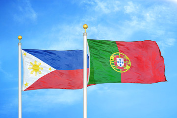 Philippines and Portugal two flags on flagpoles and blue cloudy sky