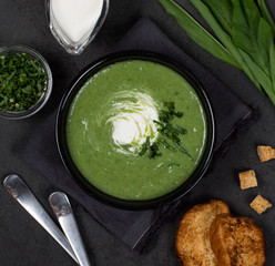 Cream soup ramson with croutons in a bowl on a dark background top view