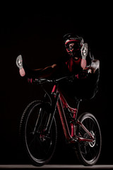 Obraz na płótnie Canvas Male bicyclist posing on dirty downhill mountain bike with legs up. Studio shot with smoke in the air