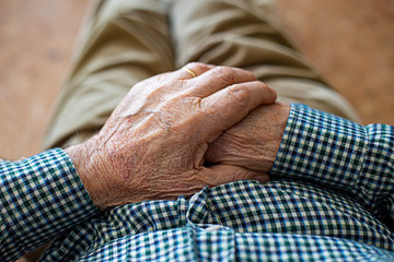 Elderly man resting in a rocking chair with a walking stick