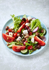 Healthy Salad with Tomatoes, Cucumber, Lettuce and Olives on bright wooden Background. Healthy Snack Idea. 