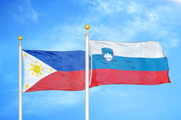 Philippines and Slovenia two flags on flagpoles and blue cloudy sky